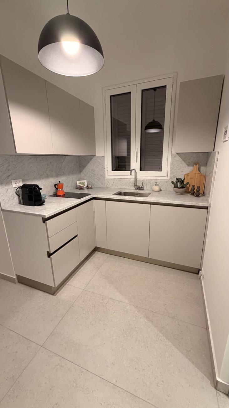 Cucina dello Studio Primo con piano in marmo, macchina espresso e lampada a sospensione