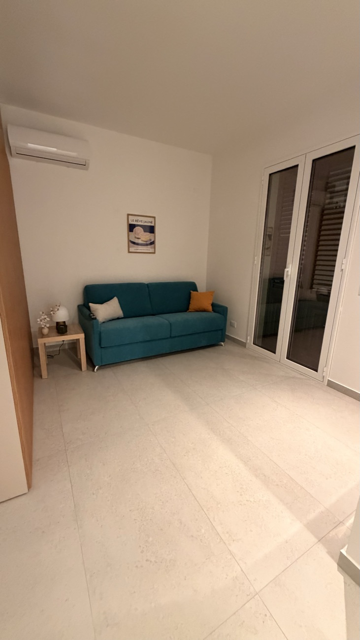 Zona giorno dello Studio Primo con divano turchese e portefinestre