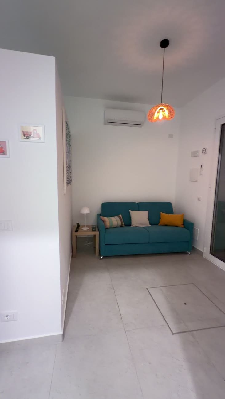 Studio Terra living area with a teal couch, pendant lamp and air conditioning